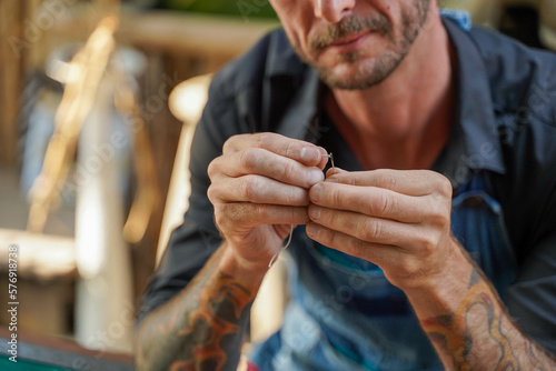 Closeup hand of leather craftsman is carefully threading a needle to sew a leather product for a customer. © Atiwat