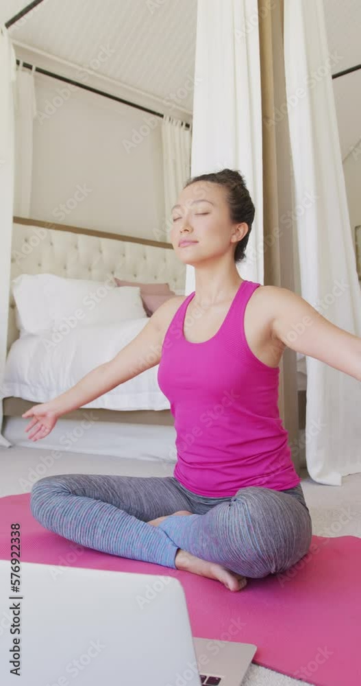 Vertical video of happy asian woman doing yoga and meditating in bedroom, in slow motion Vertical video of happy asian woman doing yoga and meditating in bedroom, in slow motion