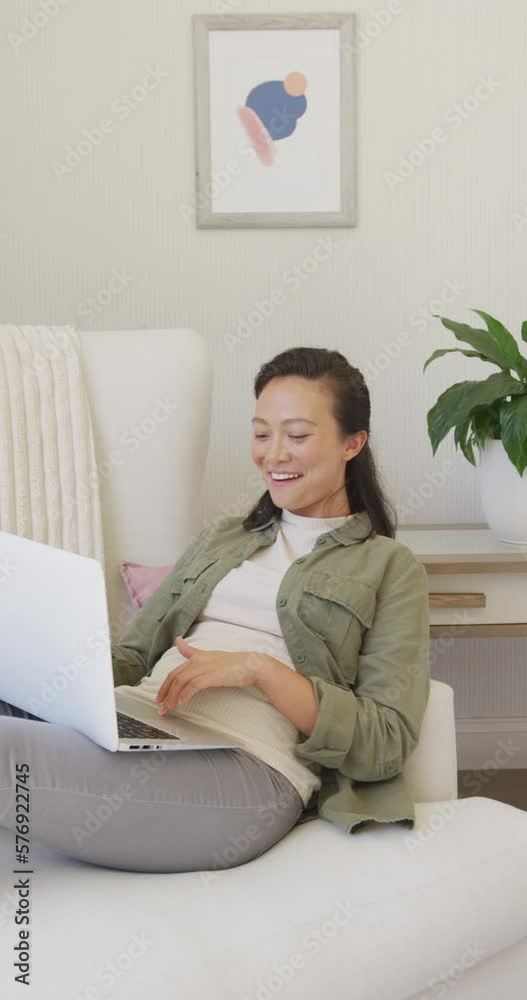 Vertical video of happy asian woman using laptop in bedroom, in slow motion Vertical video of happy asian woman using laptop in bedroom, in slow motion