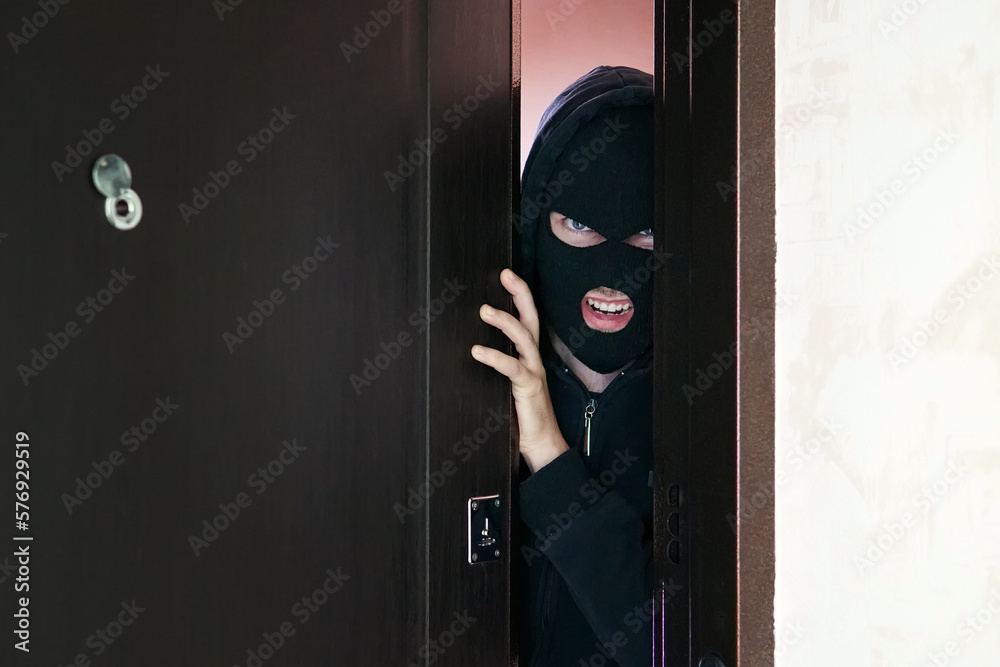 man burglar in black mask open the door stealing something from house man burglar in black mask open the door stealing something from house
