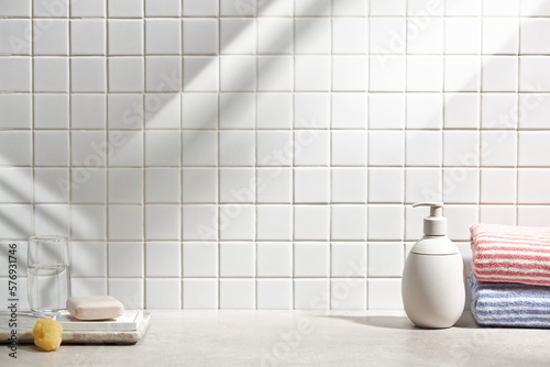 Various objects on a white tile background with warm sunlight shining through 