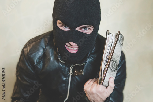 Fotografia Half shot of gloating pickpocket in black mask looking at the viewer and grinning