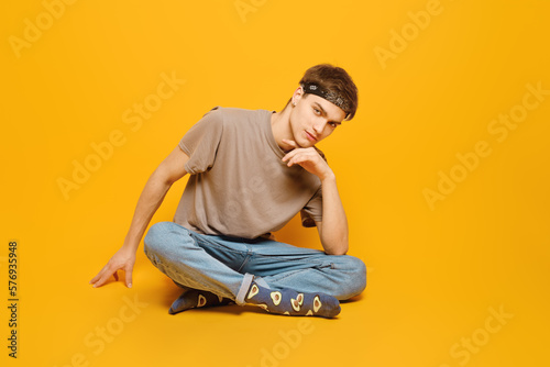 Casual young adult man sitting in a vibrant yellow studio © boomeart