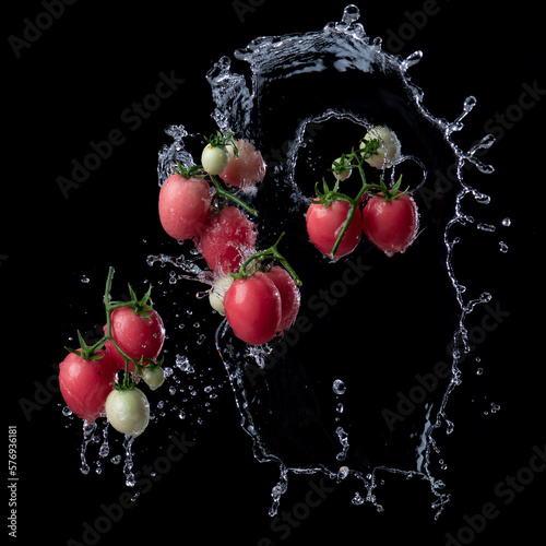 Fresh red tomato with water splash and air bubbles isolated on black background.