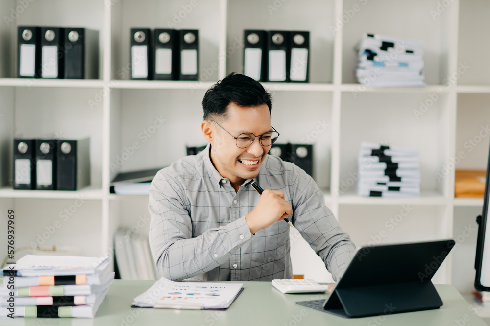 Asian business man are delighted and happy with the work they do on their tablet, laptop and taking notes at the office.. Asian business man are delighted and happy with the work they do on their tablet, laptop and taking notes at the office..