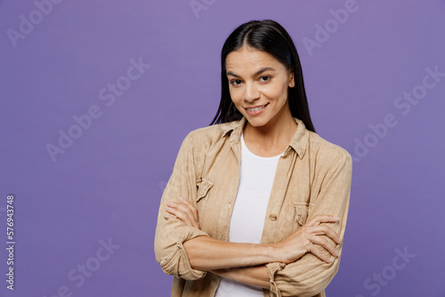 Young smiling happy fun cheerful latin woman wear light shirt casual clothes hold hands crossed folded look camera isolated on plain pastel purple color background studio portrait. Lifestyle concept.