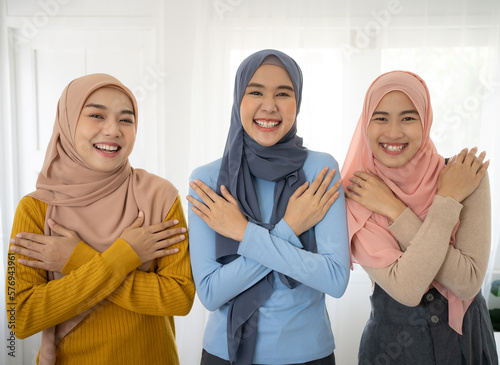 Embrace equity on multiracial Internal Women's Day. Group asian muslim lady good mood hands hug herself shoulders enjoy joyful warmth toothy smile. photo