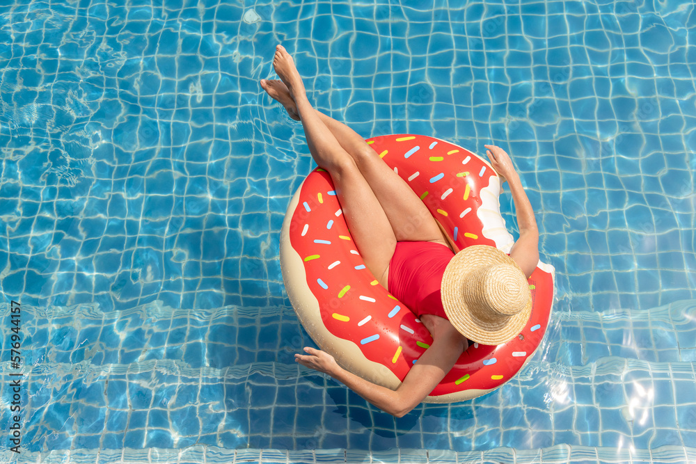 Beautiful woman with inflatable donut in pool - obrazy, fototapety, plakaty 