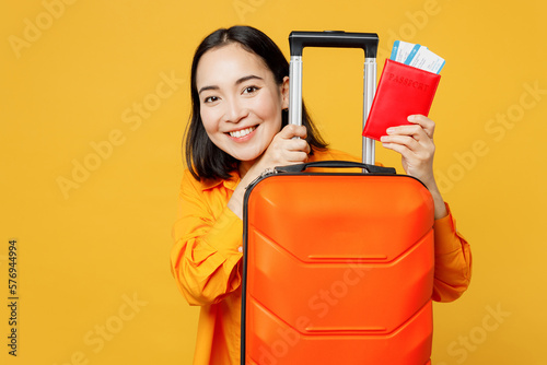 Young woman wear summer casual clothes hold passport ticket valise suitcase isolated on plain yellow background. Tourist travel abroad in free spare time rest getaway. Air flight trip journey concept. #576944994