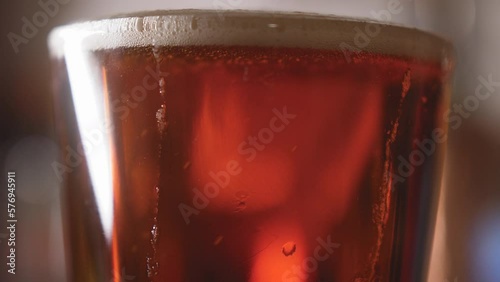 Close up of beer pouring into a pint glass and swirling bubbles rising in it 4K photo