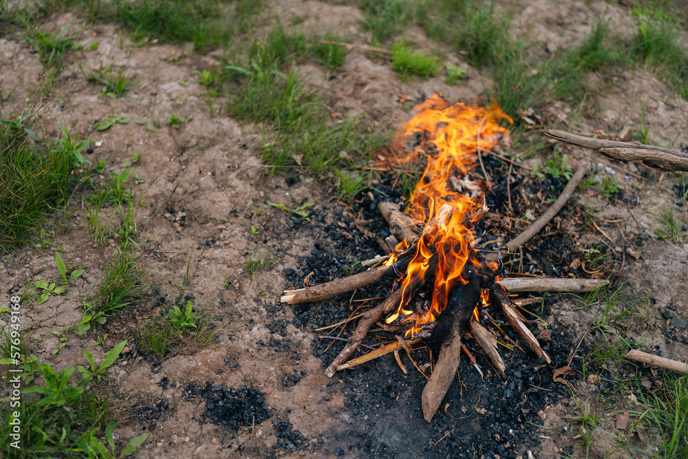 Close up high angle view of burning firewood campfire on forest ground. Closeup yellow flame burning in bonfire. Camp fire in cloudy day outdoors. Concept of lifestyle, leisure activity on nature Close up high angle view of burning firewood campfire on forest ground. Closeup yellow flame burning in bonfire. Camp fire in cloudy day outdoors. Concept of lifestyle, leisure activity on nature