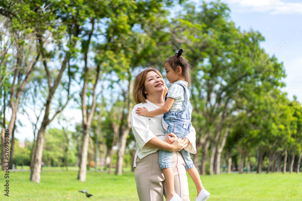 Portrait of happy love asian grandmother and asian little cute girl enjoy relax in summer park.Young girl with their laughing grandparents smiling together.Family and togetherness Portrait of happy love asian grandmother and asian little cute girl enjoy relax in summer park.Young girl with their laughing grandparents smiling together.Family and togetherness