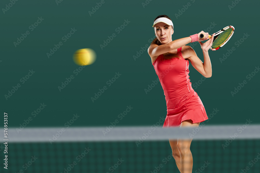Young attractive sporty woman playing tennis and beating ball with racket