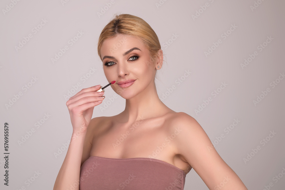 Studio portrait of beautiful woman with red lipstick. Beautiful young woman applying lipstick on her lips, isolated on studio background. Studio portrait of beautiful woman with red lipstick. Beautiful young woman applying lipstick on her lips, isolated on studio background.