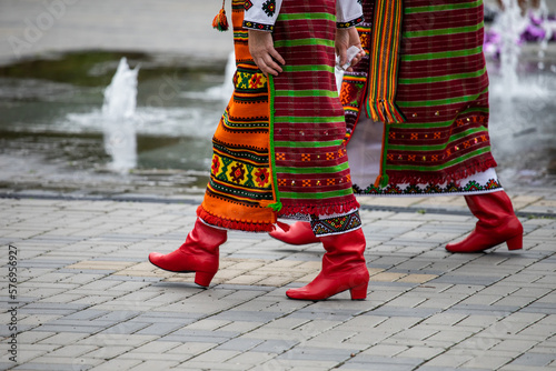 Two people walking in the street. Red boots. Ukrainian national clothes. Street festival