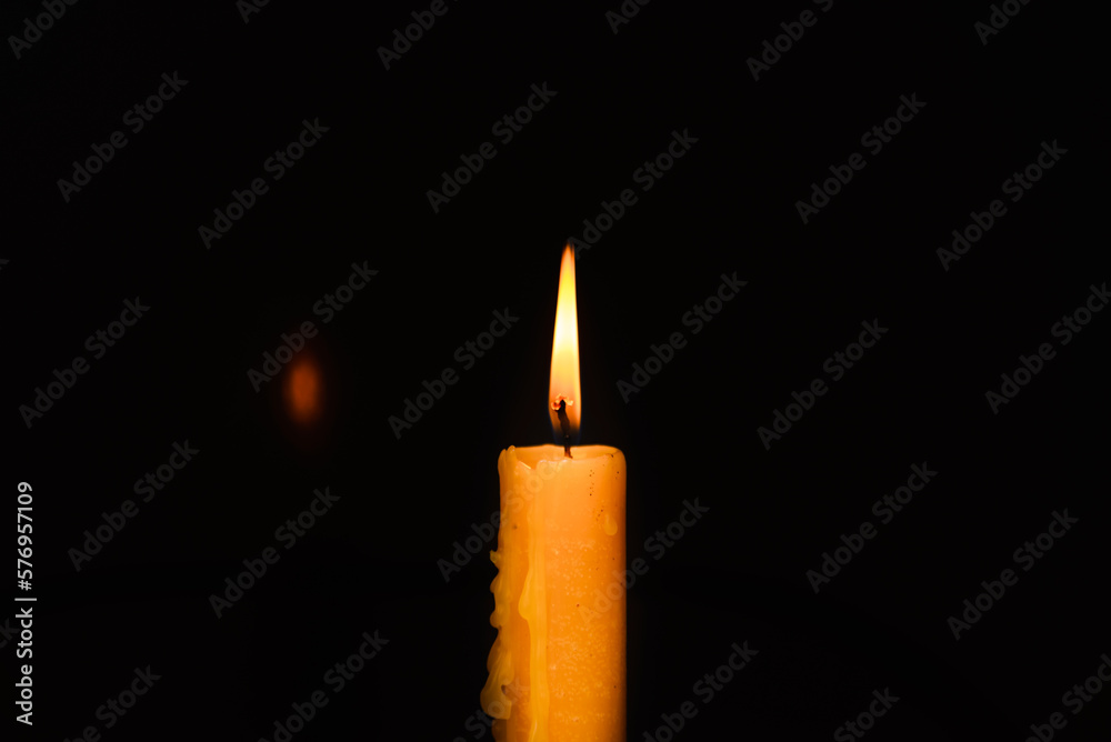 Old lighting a candle in the dark.Close up single candle light and flame on black background. Melted Wax Candle light border design. Burning at Night, Darkness.Candlelight.Copy space. Old lighting a candle in the dark.Close up single candle light and flame on black background. Melted Wax Candle light border design. Burning at Night, Darkness.Candlelight.Copy space.