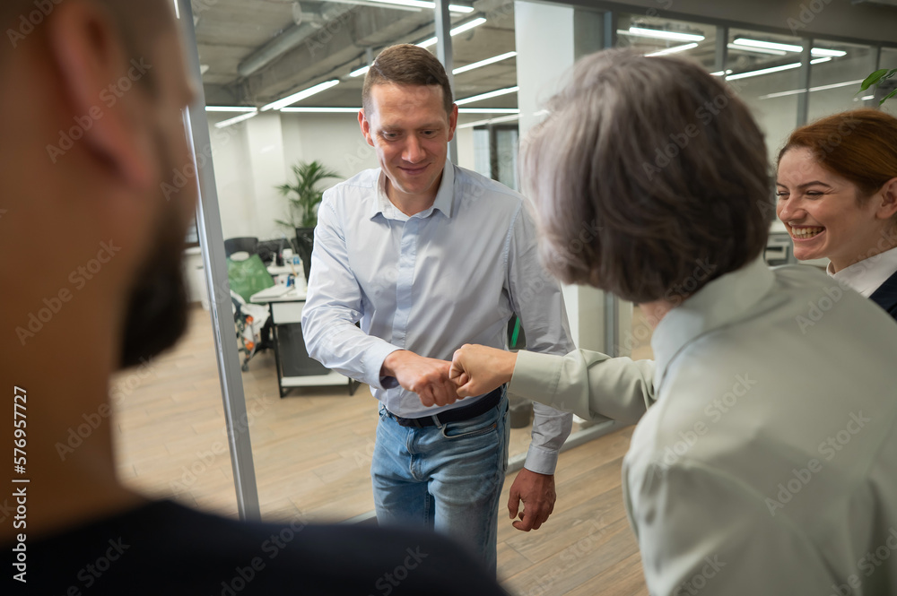 Obraz premium Caucasian man bumping his fists with colleagues as a sign of success. 