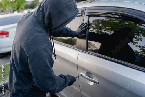 Robber breaking into a car at the parking lot.