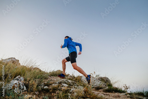 male runner running uphill in blue sky background