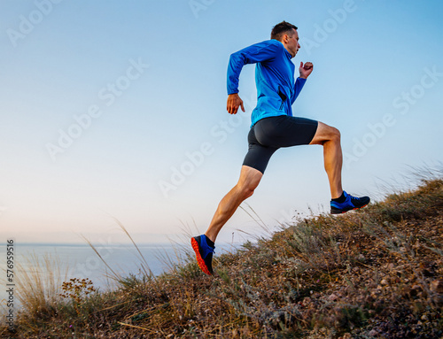 Tableau sur toile male runner running uphill in background sky and sea