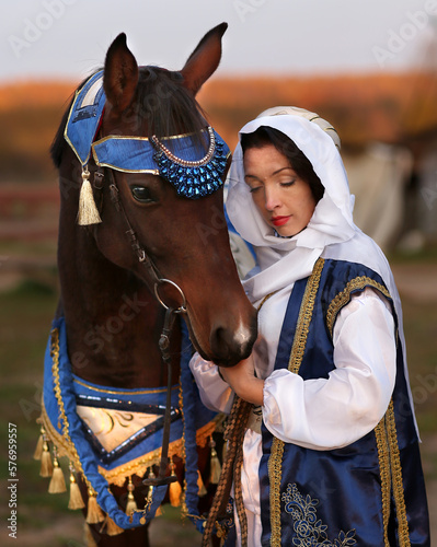 a dark-haired girl in Arab clothes and a horse