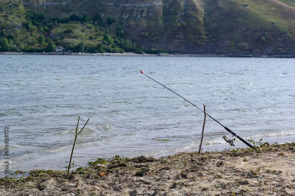 Fishing rods and fishing gear on the river bank, lake coast close up wave