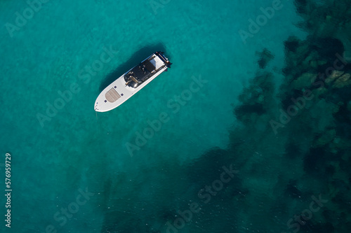 Big white motor boat anchored in coral sea top view. White modern boat with motor on blue water aerial view.