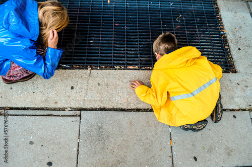 A girl and boy peer in a sidewalk vent in Washington D.C. during the fall photo