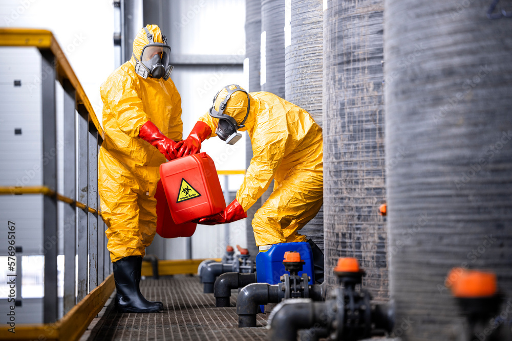 Factory workers carefully handling toxic and dangerous biohazardous waste in chemicals factory. - obrazy, fototapety, plakaty 