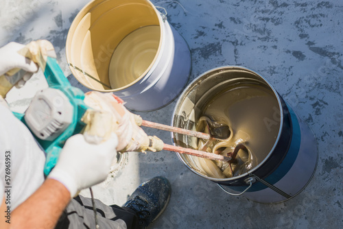 Worker mixing yellow epoxy resin with the mixer in a bucket photo