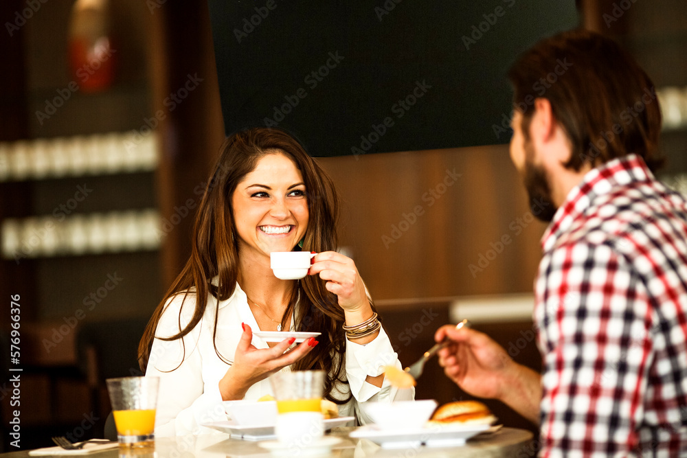 A young couple sits opposite sides of a table has snacks, fruit juices and cup of teas. A young couple sits opposite sides of a table has snacks, fruit juices and cup of teas.