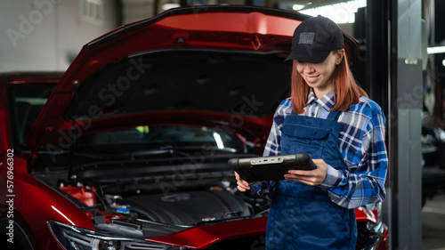 Caucasian female auto mechanic uses a special computer to diagnose faults. 