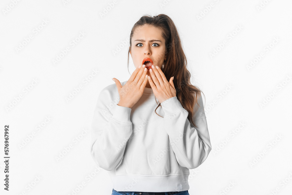 Portrait of girl looking shocked after hearing something, touches her mouth and looks speechless, stands over white background Portrait of girl looking shocked after hearing something, touches her mouth and looks speechless, stands over white background