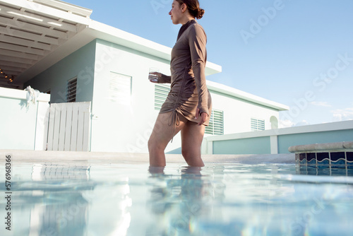 Solo woman with drink enjoying a dip in the pool in Puerto Rico photo