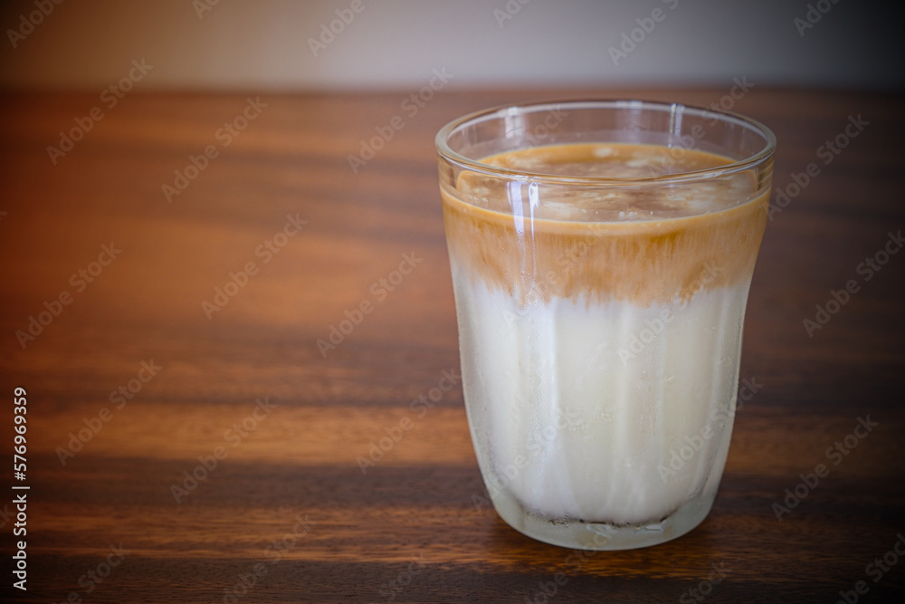 Dirty coffee in transparent glass on brown wooden table with copy space Dirty coffee in transparent glass on brown wooden table with copy space