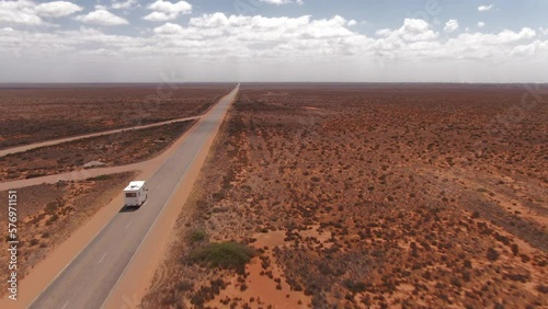 Campervan driving on an empty long straight road in a barren environment in South Australia. Drone follow shot photo