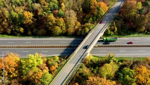 Aerial drone shot showing traffic on a road crossing next to a forest photo