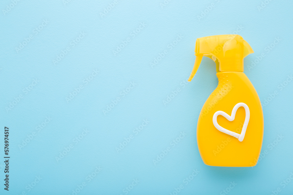 Heart shape created from white cream on yellow spray bottle of sunscreen. Light blue table background. Pastel color. Care about body skin protection in summer. Empty place for text. Top down view. Heart shape created from white cream on yellow spray bottle of sunscreen. Light blue table background. Pastel color. Care about body skin protection in summer. Empty place for text. Top down view.