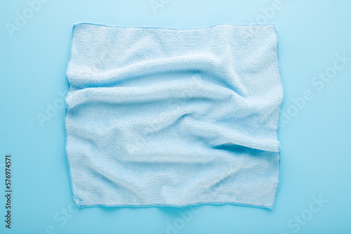 Wrinkled dry soft microfiber rag for different surfaces wiping. Closeup. Light blue table background. Pastel color. Top down view.