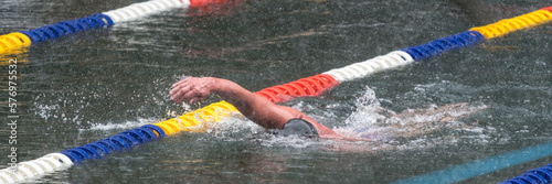 A man swimming in a lake at an ice swimming competition while snow is falling