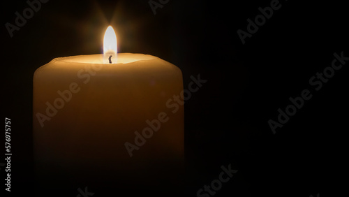 A lit candle with a black background.