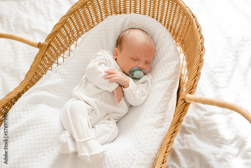 Εκτύπωση καμβά Cute baby sleeping in straw cradle wearing pajamas and with pacifier top view