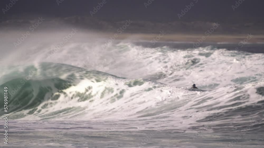 Surfer finishes the ride by jumping over the wave, where jetski driver is waiting to take him to safety. Nazare, big waves surfing Surfer finishes the ride by jumping over the wave, where jetski driver is waiting to take him to safety. Nazare, big waves surfing