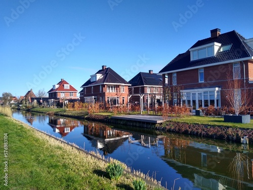 Several similar red brick residential houses at the canal on a sunny day 