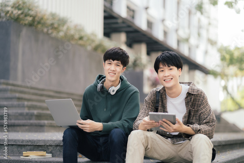 Asian students joining study book, smiling with laptop computer tablet at high school university, college, vacation, summer vacation.