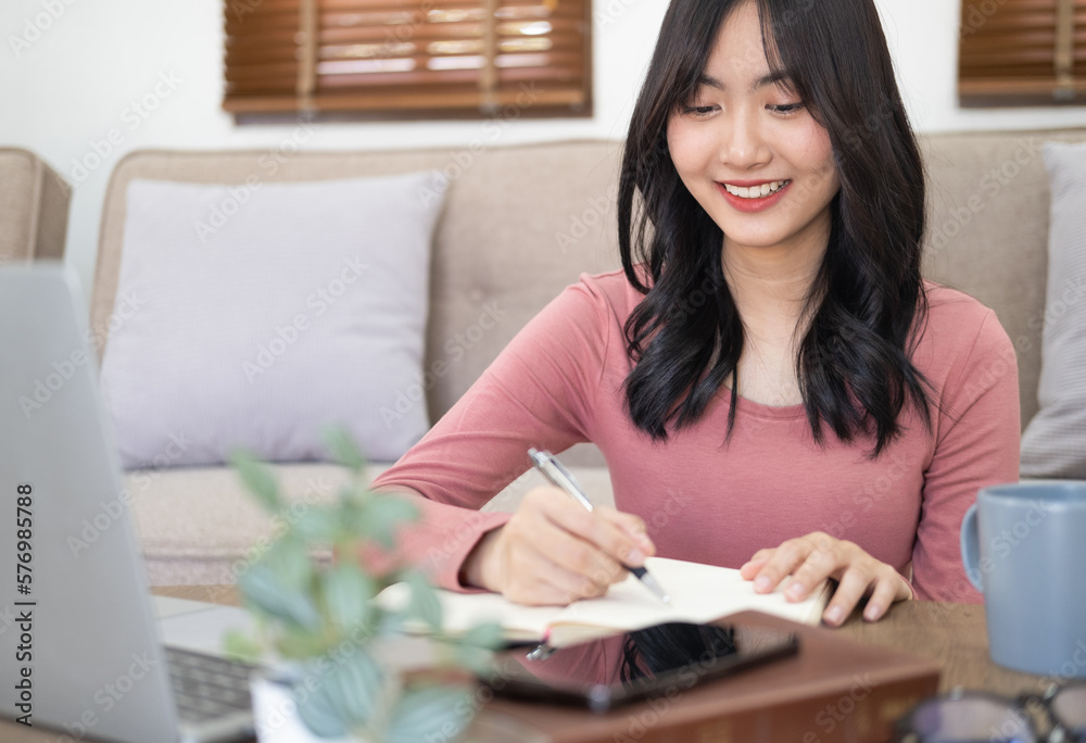 Young student watching lesson online and studying from home. Young woman taking notes while looking at computer screen following professor on video call. Girl studying from home on computer. Young student watching lesson online and studying from home. Young woman taking notes while looking at computer screen following professor on video call. Girl studying from home on computer.