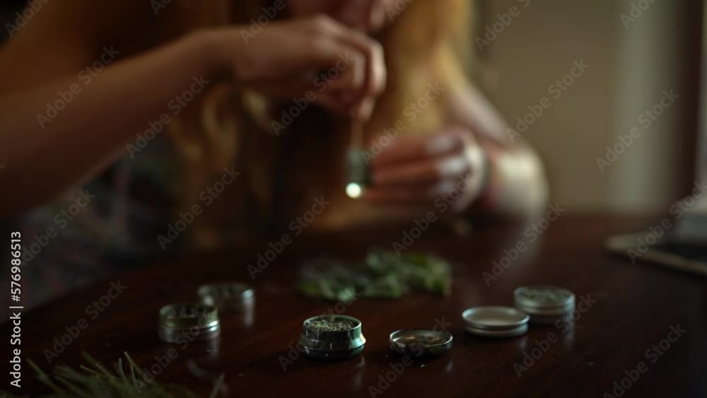 woman prepares herbs for tobacco with the help of a herb grinder to grind a cannabis. woman prepares herbs for tobacco with the help of a herb grinder to grind a cannabis.