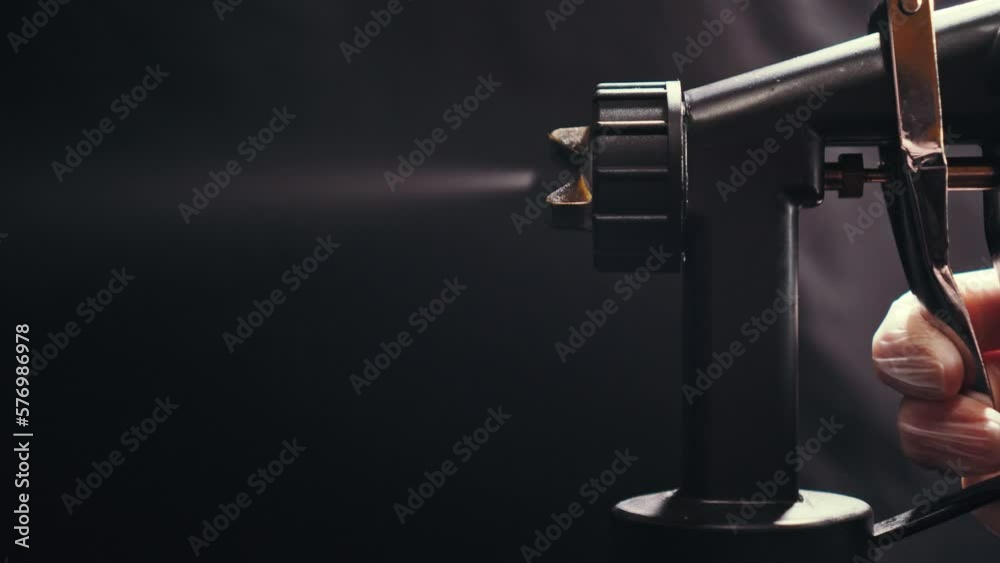 Cosmetologist using airbrush for spray tan in beauty salon. Close up of hand.