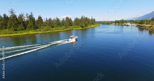 Motor Boat Sailing Fast Along Waterway River at Beautiful Summer Day in Port Alberni Region British Columbia Canada, Aerial Tracking View photo