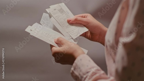 Housewife analyzes the prices of goods, looking at the cash receipt after purchase. A young girl with a paper bag in her hands looks at a check with prices.